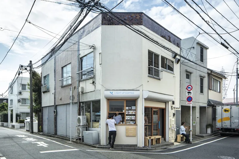 Street corner facade of a narrow white building with a small shopfront beneath overhead power lines