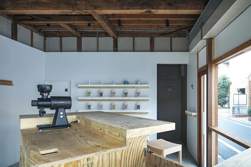 Interior counter with plywood surface and coffee grinder beneath exposed timber ceiling beams