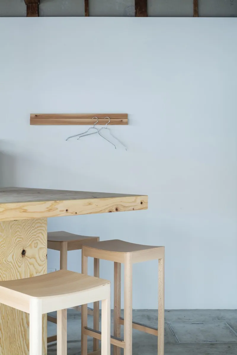 Plywood seating nook with timber stools and simple wall-mounted coat hooks