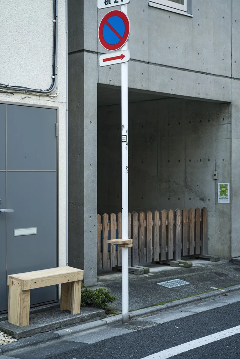 Street-facing concrete alcove with timber slat screening and simple plywood bench