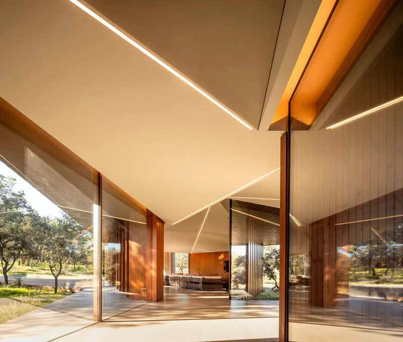 Open glazed corner with sliding timber doors and linear ceiling lighting beneath the angled roof plane