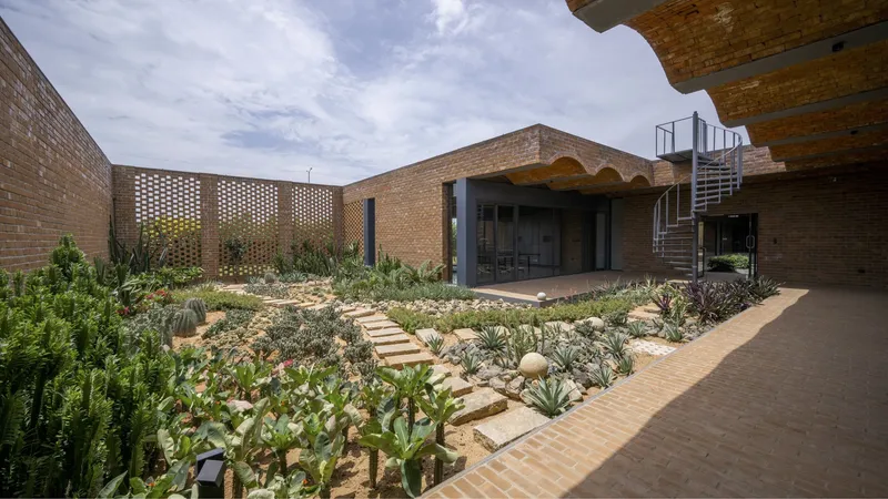Succulent garden with stone stepping path leading to perforated brick screen and metal stair