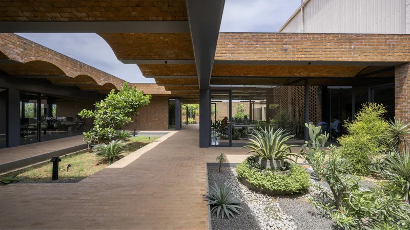 Covered walkway with scalloped brick arches sheltering planted beds and paved paths below