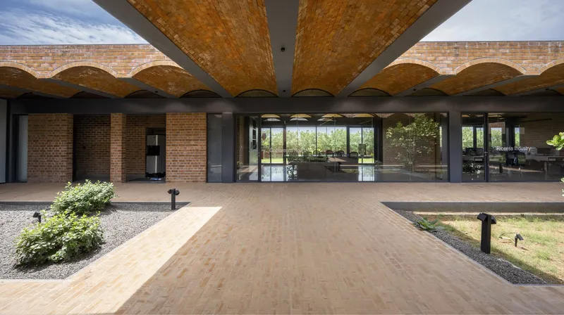 Symmetrical view along brick-paved path beneath radiating vaulted canopy toward glazed interior