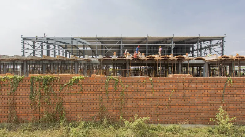 Exterior view of the exposed steel frame and brick perimeter wall with young climbing plants