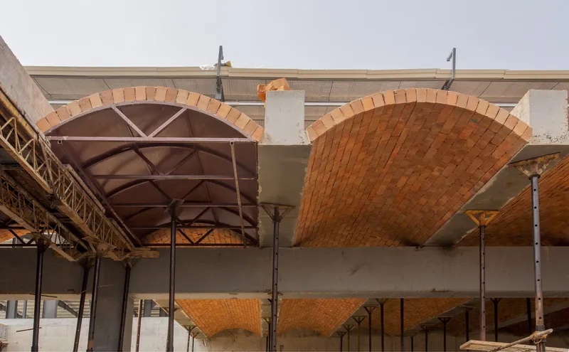 Construction detail showing the curved brick vault shells supported by concrete beams and steel bracing