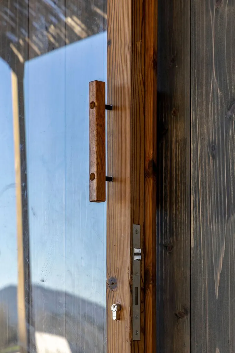 Close-up of carved wood door handle mounted on vertical timber siding with metal lockset