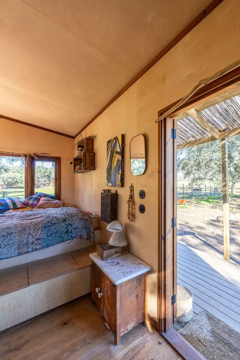 Interior bedroom with plywood ceiling and glazed doors opening to a sunny deck