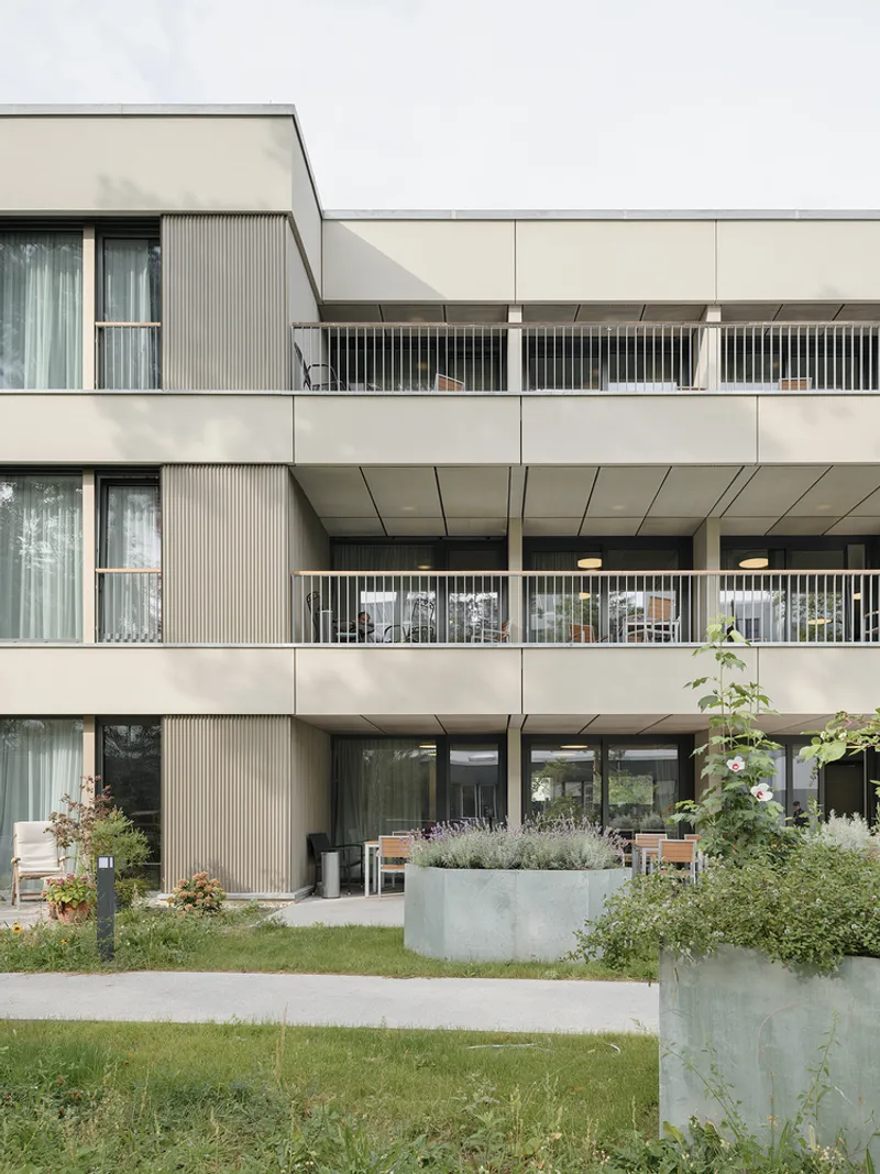 Stacked balconies with metal railings above concrete planters filled with lavender and grasses