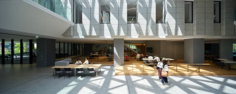 Interior seating area beneath a skylight with triangular shadow patterns falling across visitors and tables
