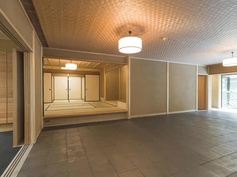 Foyer with woven ceiling pattern and opening to raised tatami room under pendant lighting