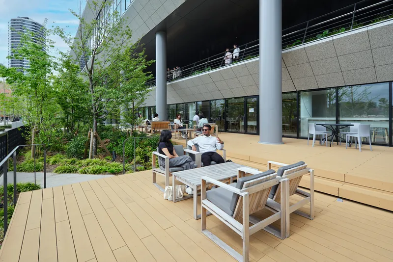 Elevated timber deck terrace with outdoor furniture and planted beds under a partly cloudy sky