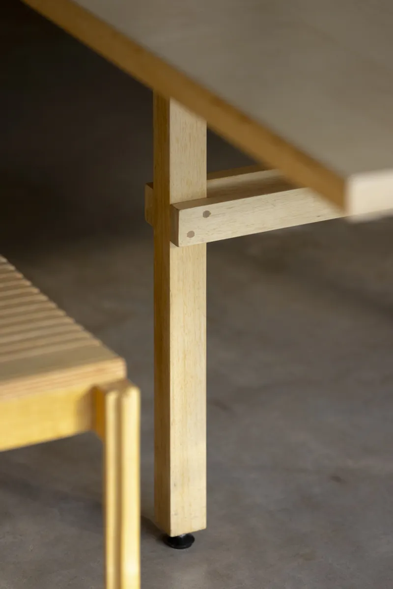 Timber post and beam joinery detail with shadow falling across grey wall surface
