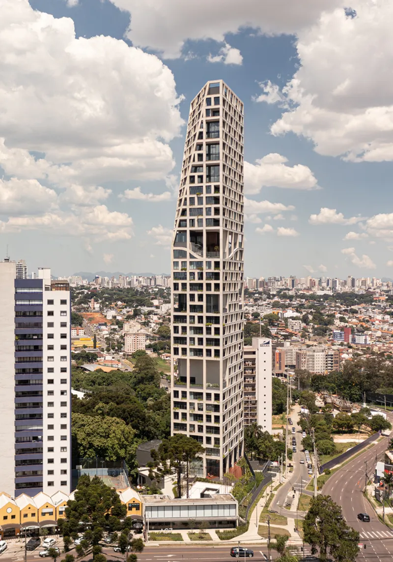 Twisted residential tower with a gridded facade rising above an urban landscape under scattered clouds