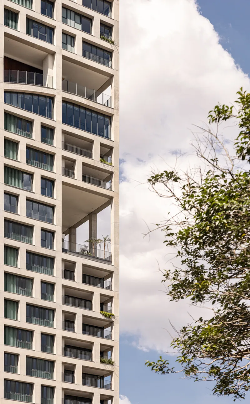 Facade detail with deep terraces and the adjacent leafy tree canopy at mid-height