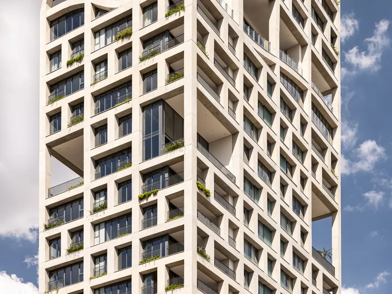 Close-up of the diagonal concrete frame pattern with recessed balconies and greenery in afternoon light