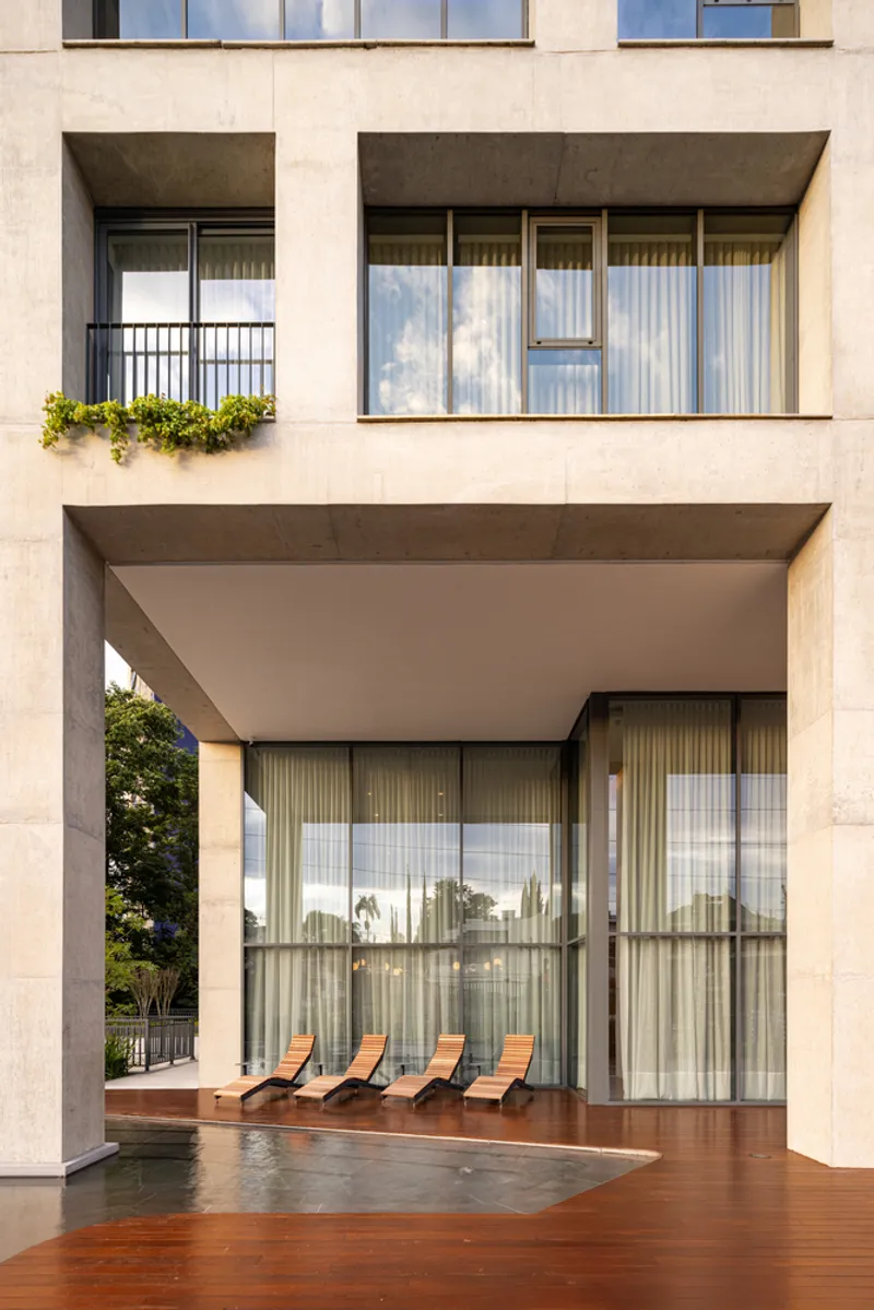 Private terrace with timber deck, swimming pool, and four lounge chairs behind floor-to-ceiling glass and curtains