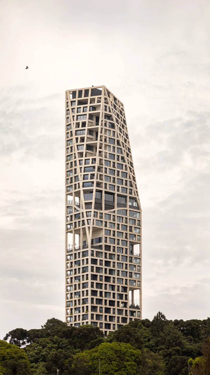 Twisted residential tower with exposed concrete structural grid and recessed balconies under overcast skies
