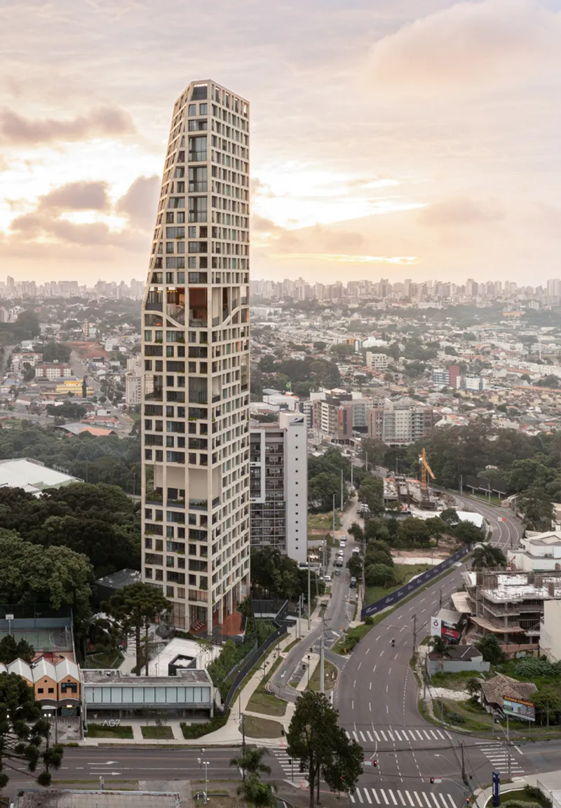 Aerial view of the tapering tower with staggered concrete frames along a major roadway at dawn