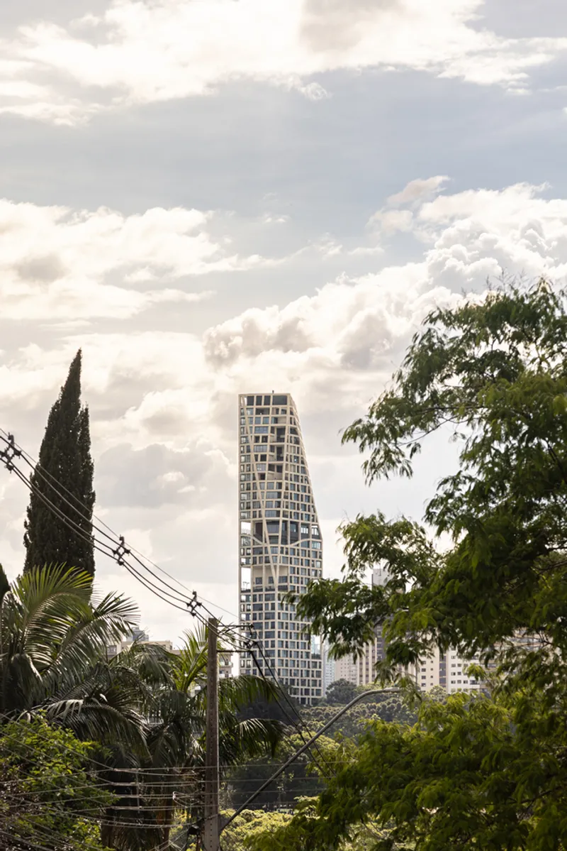 Distant view of the tower emerging above palm trees and utility lines under scattered clouds