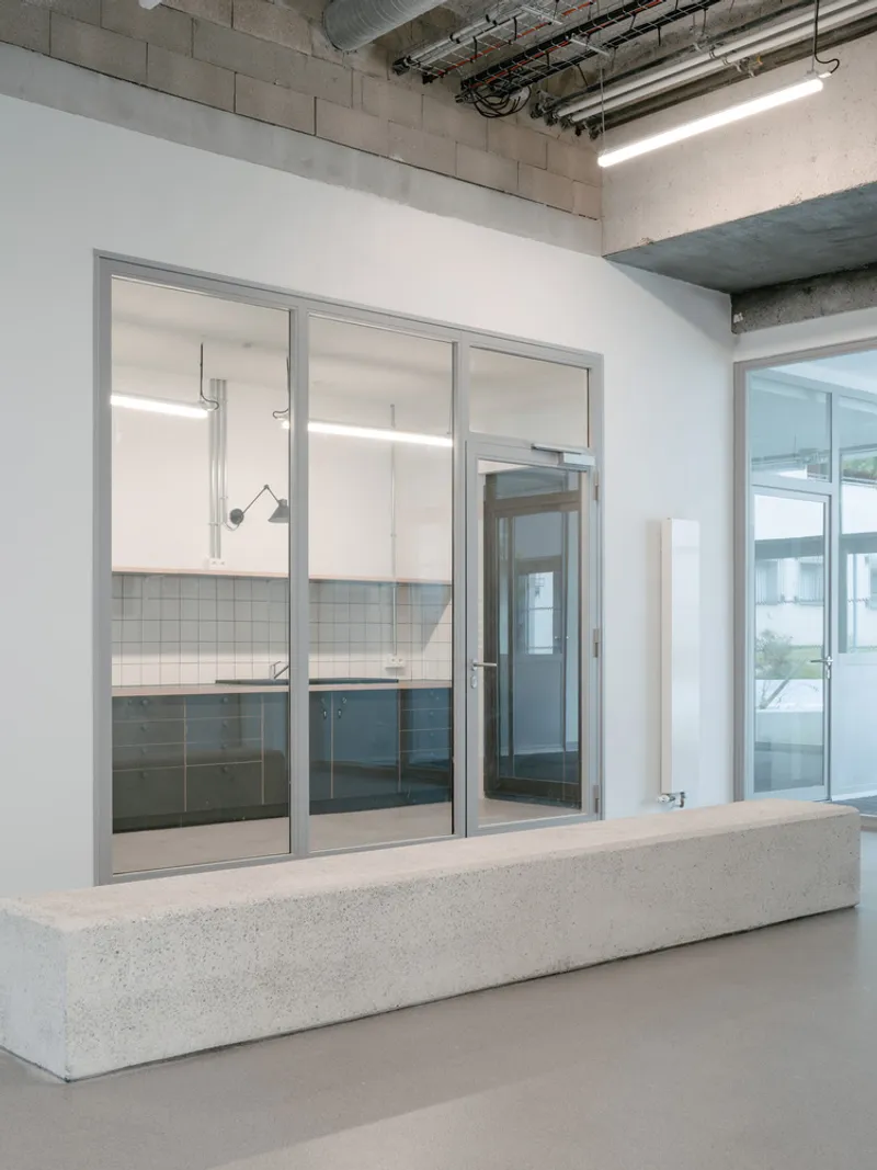 Interior view of the glazed partition wall with exposed concrete ceiling and mechanical systems