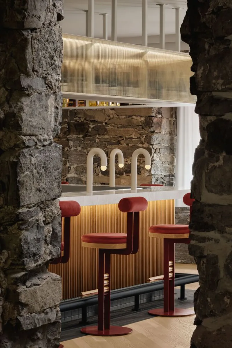 View through weathered stone opening toward bar counter with curved tap fixtures and backlit ribbed panels