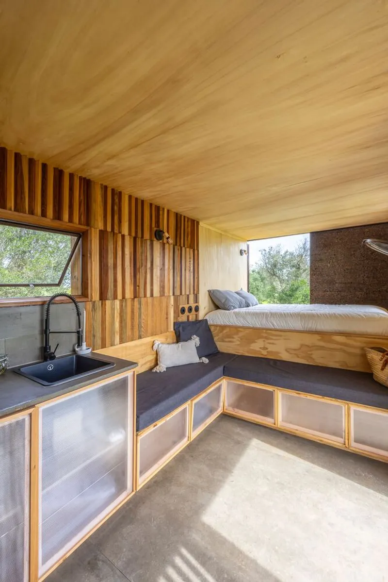 Compact interior showing kitchenette, plywood storage and raised sleeping platform with concrete floor