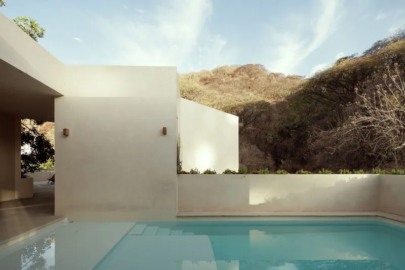 Pool courtyard framed by white stucco walls with dry hillside in the background