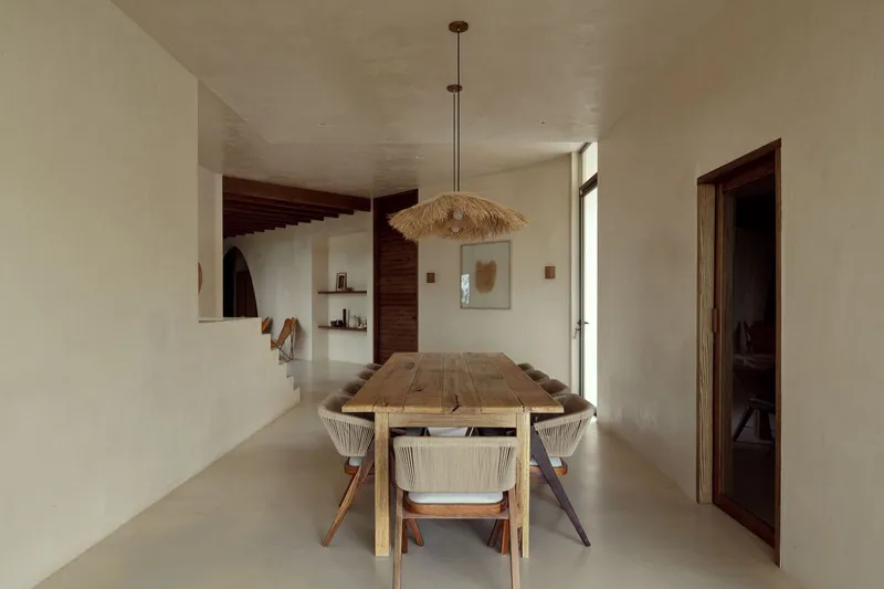 Dining area with timber table and raffia pendant fixture opening to adjacent living spaces