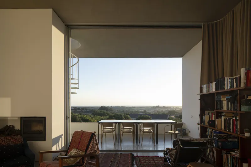 Open terrace with dining table framing a panoramic view across the valley at sunset