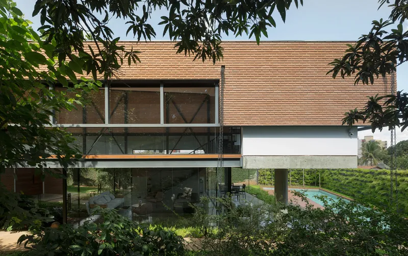 Elevated volume clad in horizontal wood slats with glazed lower level and framed by overhanging tree branches