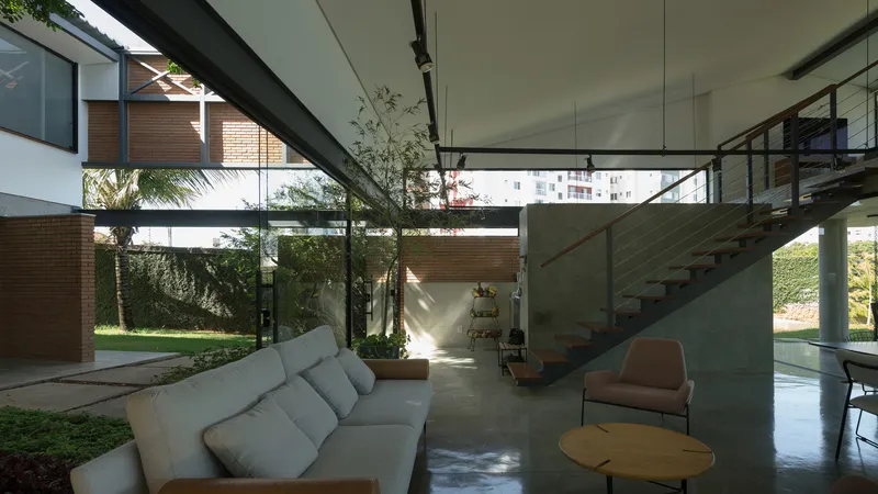 Double-height living space with concrete stair and ceiling framing views to planted courtyard beyond