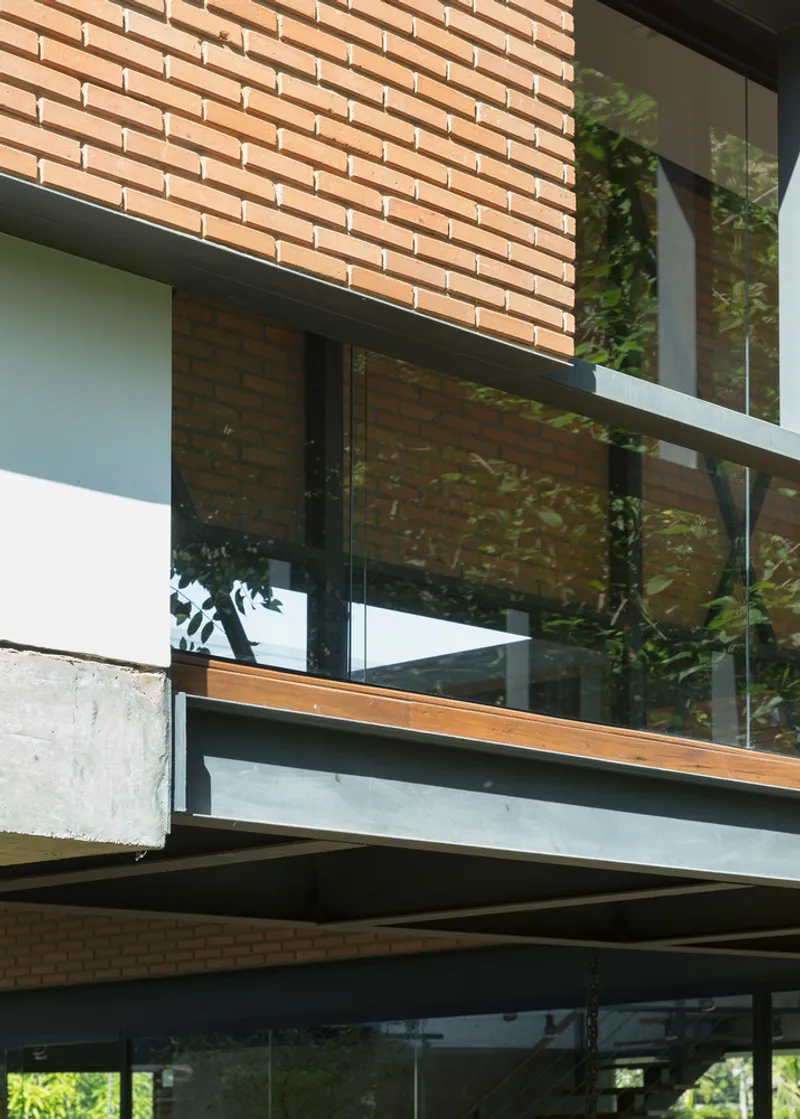Layered facade detail showing steel frame supporting brick cladding above glass balustrade and cantilevered slab