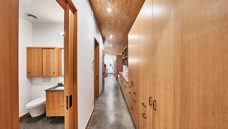Interior hallway with plywood vaulted ceiling and wood cabinetry lining polished concrete floor