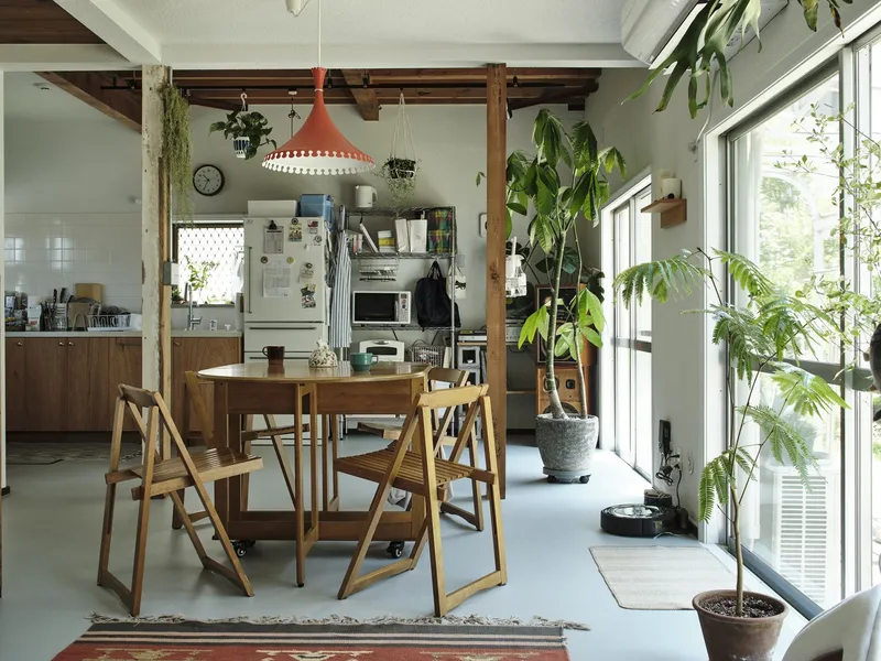 Dining area with exposed timber ceiling beams and floor-to-ceiling windows opening to a planted courtyard