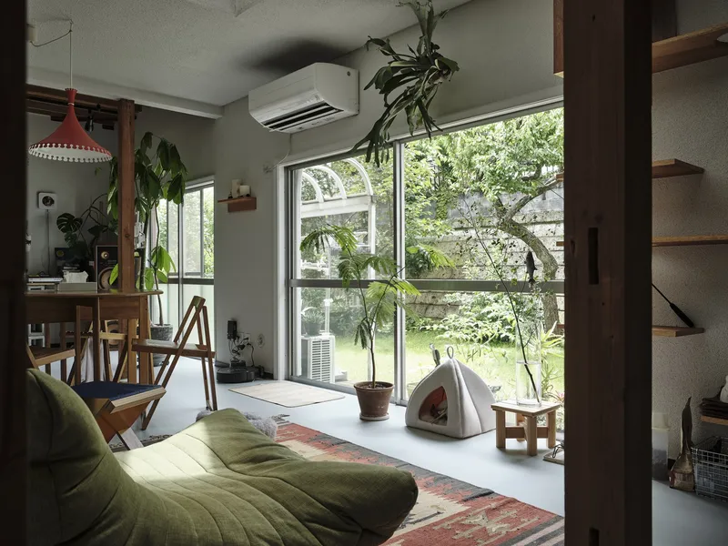 Open living space with full-height glazing overlooking a garden with potted plants and hanging greenery