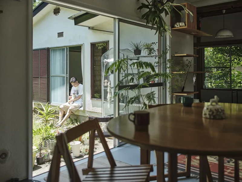 Dining table looking out to a raised threshold where a child sits in bright daylight