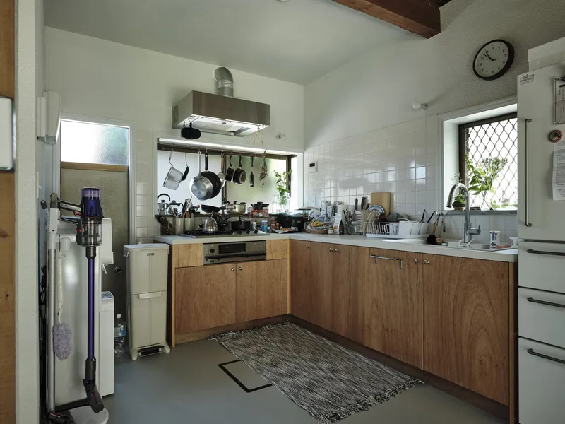 Compact kitchen with white subway tile backsplash and timber cabinetry under exposed wood beams