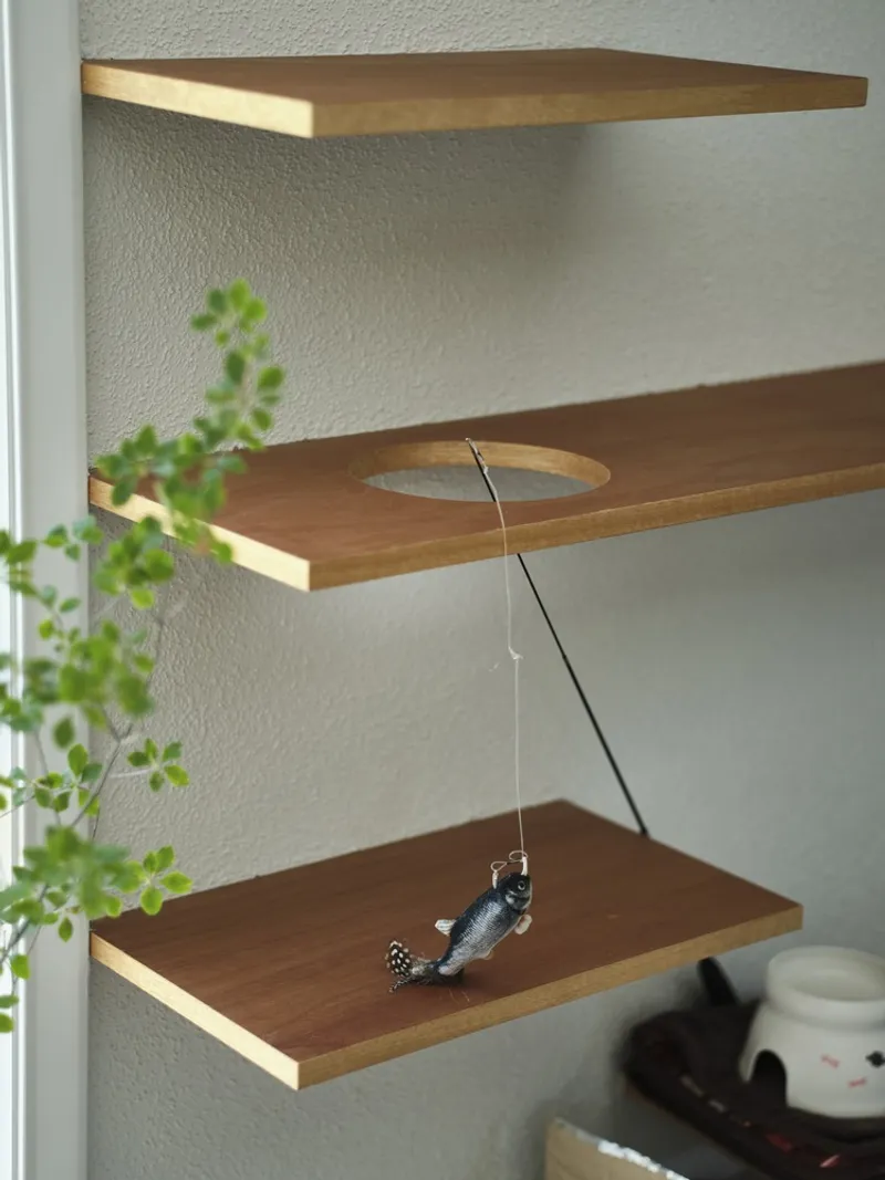 Floating timber shelves mounted on white plaster wall with hanging mobile and trailing plants