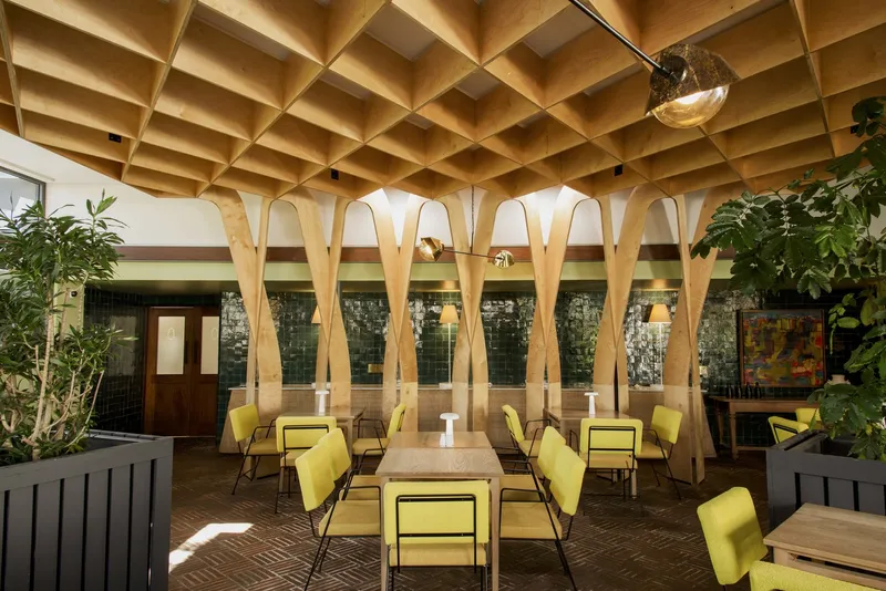 Interior courtyard with laminated timber arches and coffered ceiling above yellow seating