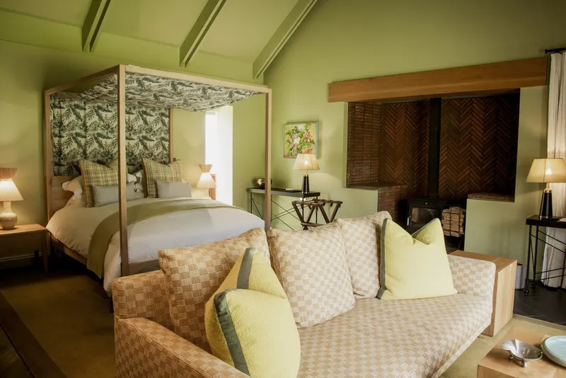 Bedroom suite with four-poster bed and herringbone timber panel beside sofa