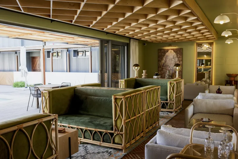 Living area with timber lattice ceiling grid and rattan-framed sofas opening to courtyard through sliding glass doors