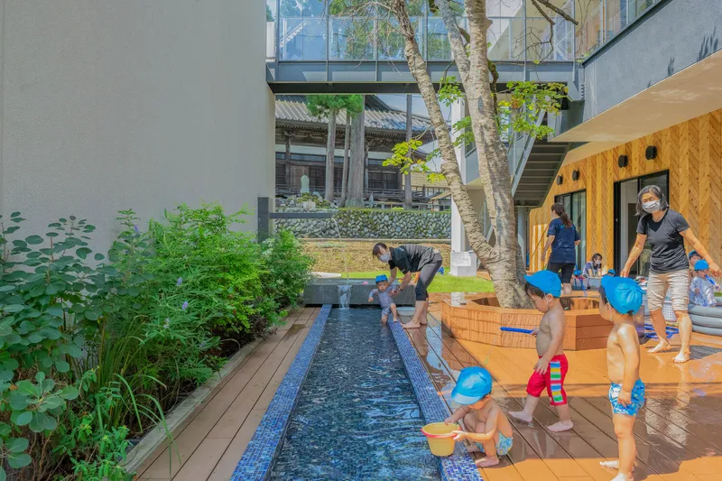 Courtyard with a blue-tiled water channel bordered by timber decking and children gathered around it