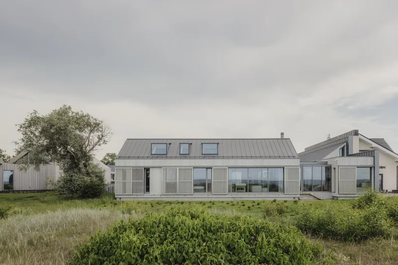 Garden view of the corrugated metal facade with dormer windows under an overcast sky