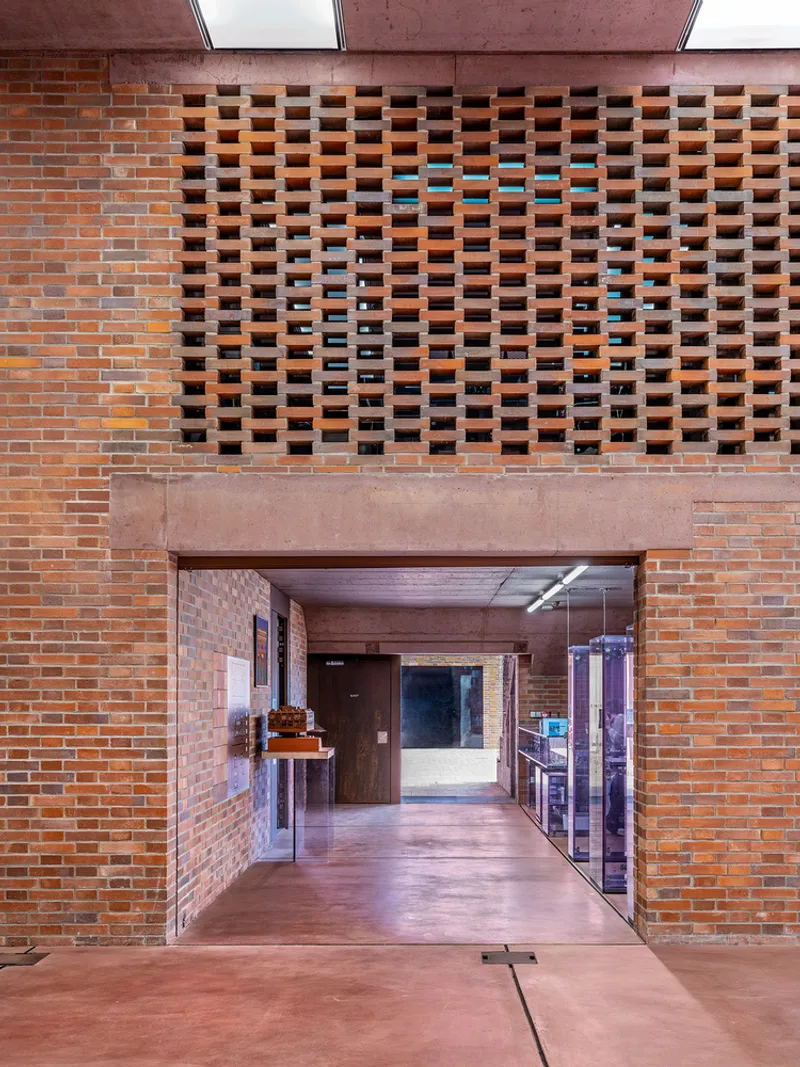Brick facade with perforated bond pattern above a passageway framed in corten steel with skylight above