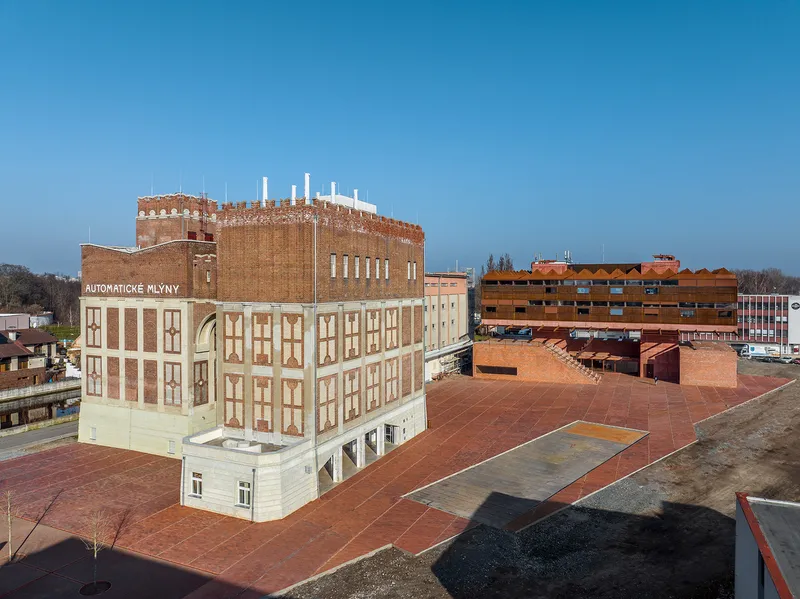 Elevated view of a brick-paved courtyard surrounded by converted industrial buildings with patterned brick facades