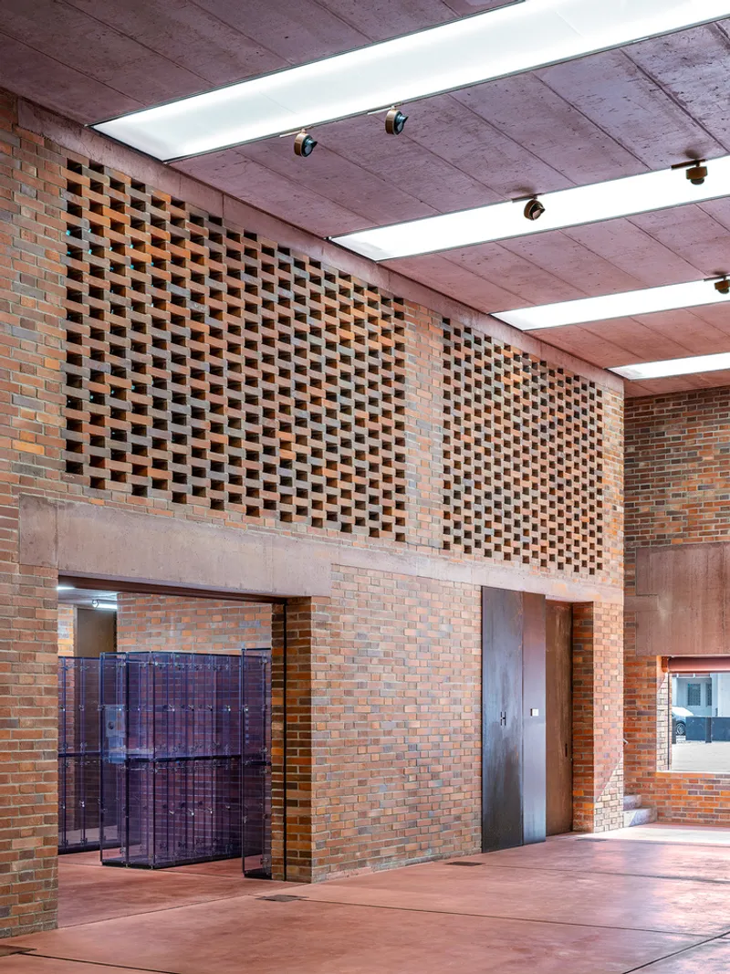 Double-height lobby space with perforated brick screen wall above glazed entrance doors