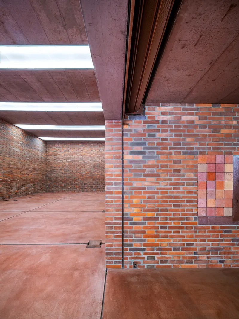 Interior courtyard with multi-toned brick walls and pillar under a coffered board-formed concrete ceiling with skylights