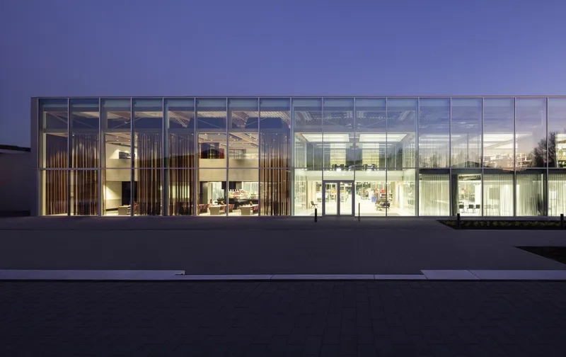 Glazed facade with vertical timber screens and illuminated interior spaces at dusk