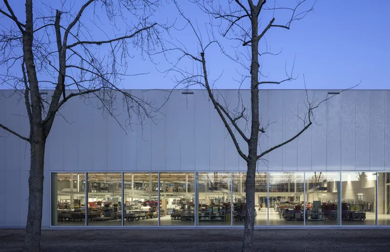 Paneled metal facade with transparent band revealing the library workspace behind winter trees